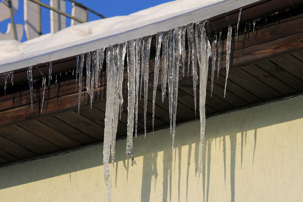Frozen gutter with icicles and ice blockage, a winter issue that could result in ceiling leaks if not addressed.