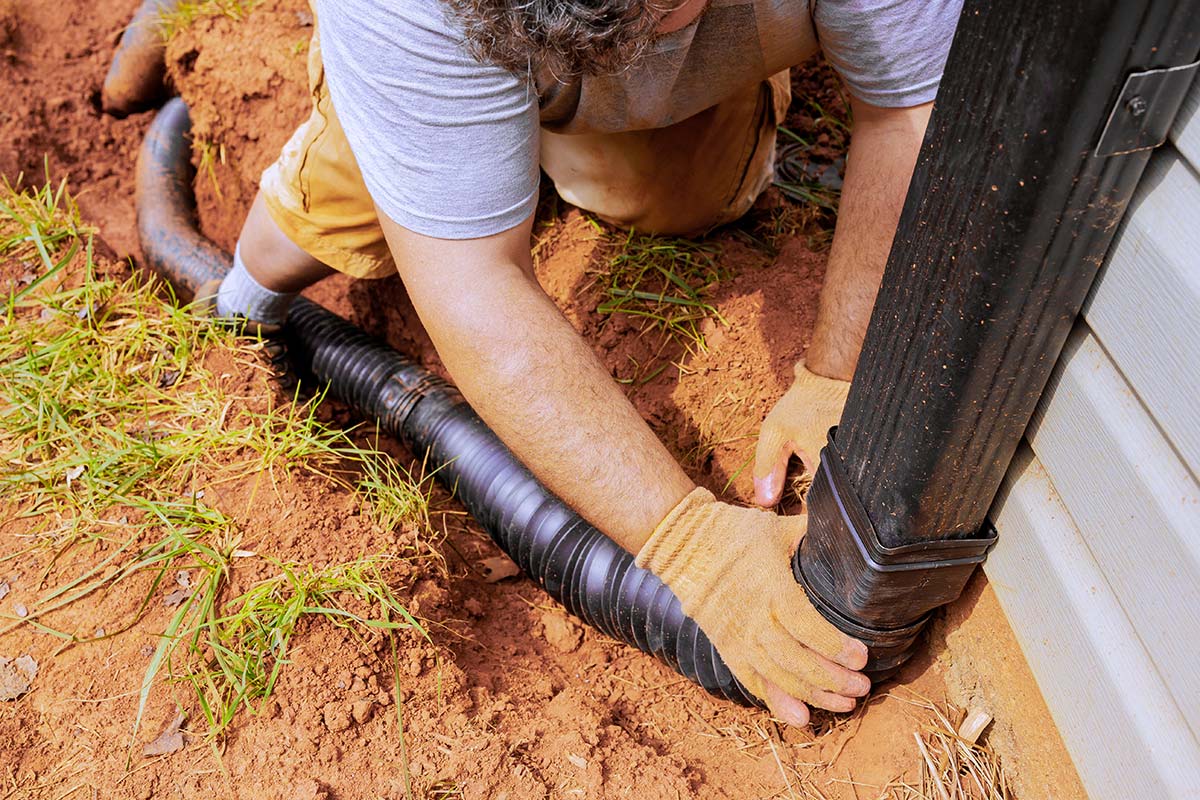 Downspout Problems being fixed with buried gutter drainage pipe installation - keeping runoff away from a home's foundation.